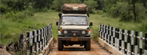 A jeep navigating a bridge above a river, illustrating the adventurous spirit of driving in Uganda.
