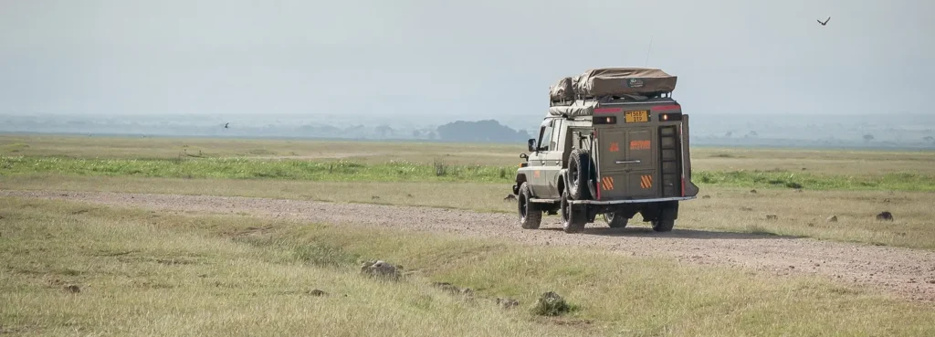 A truck carrying luggage drives along a dirt road, showcasing rural travel in Uganda. Is Uganda safe for such journeys?