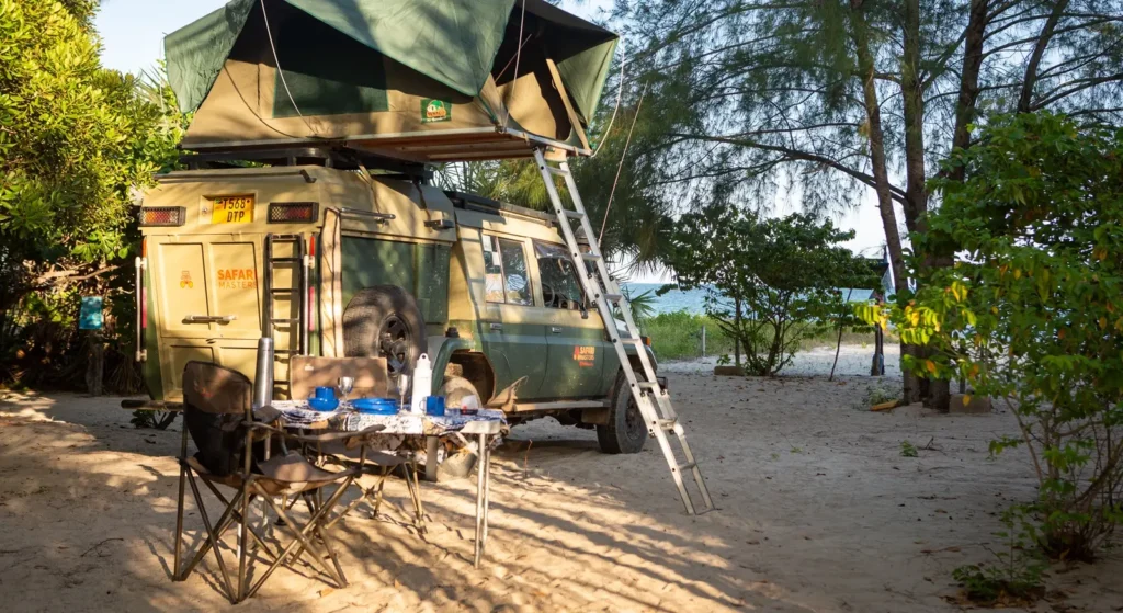 A green tent rests atop a truck, illustrating an adventurous camping experience related to uganda self drive cost.